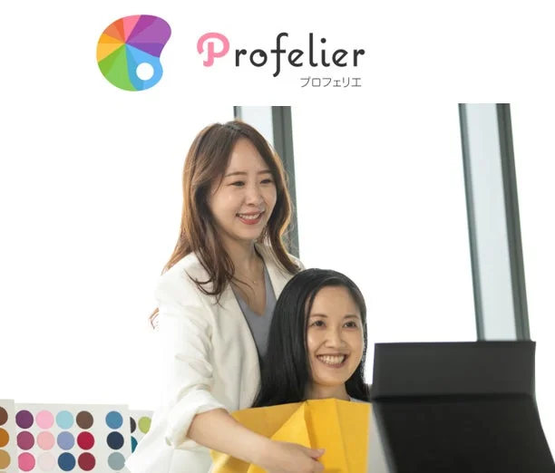 パーソナルカラー診断を行う二人の女性。一人がもう一人にカラー診断を提供し、笑顔で向き合っています。カラーパレットが手前にあり、上部には「Profelier プロフェリエ」のロゴが表示されています。
