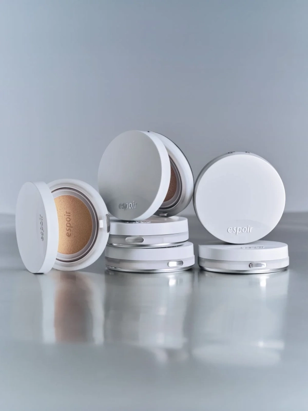 白いコンパクト型化粧品「espoir」が複数配置されたスタジオ撮影の写真