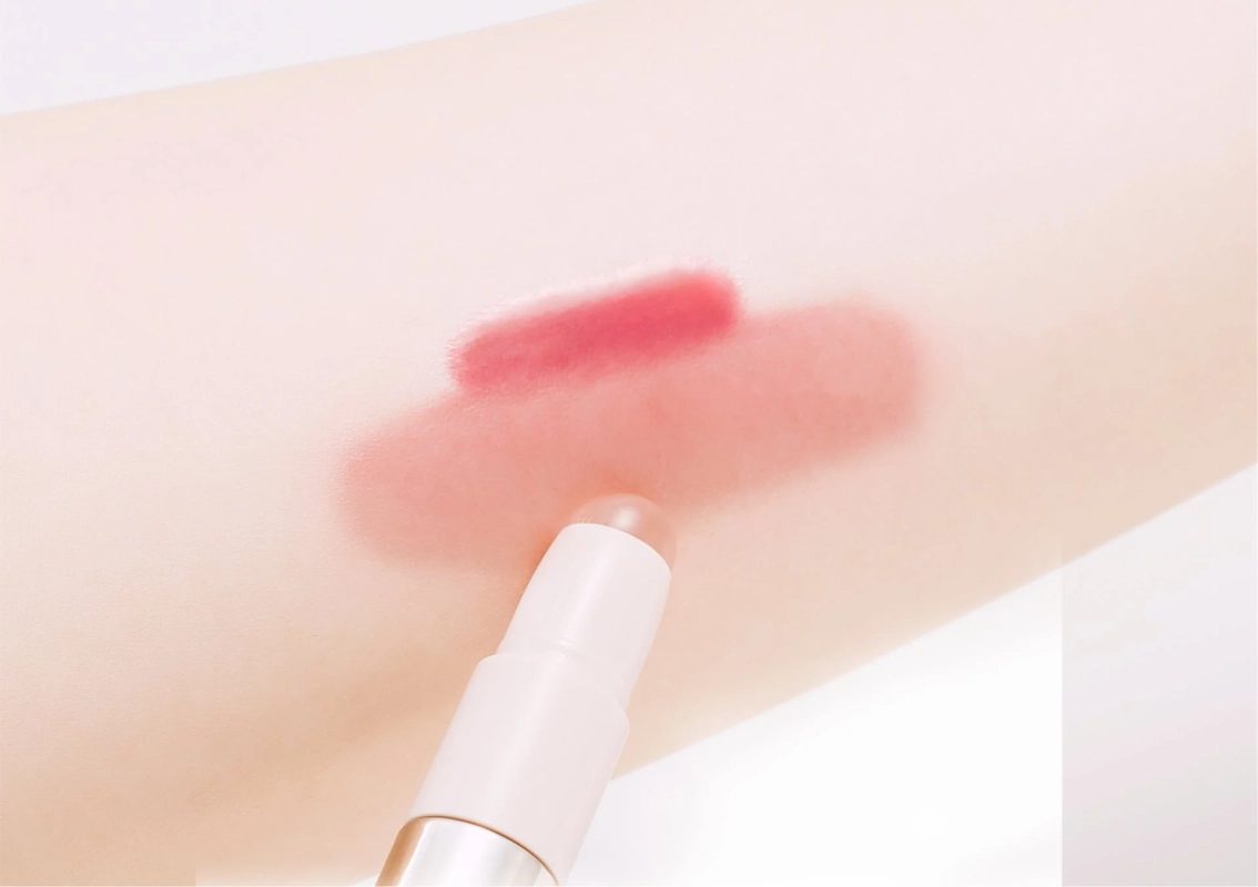 ピンク色のスティック状の化粧品を腕に塗っている画像