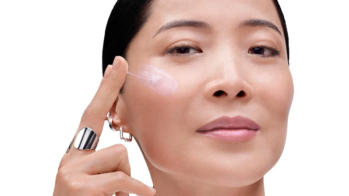 女性が顔にピンク色のクリームを塗布している