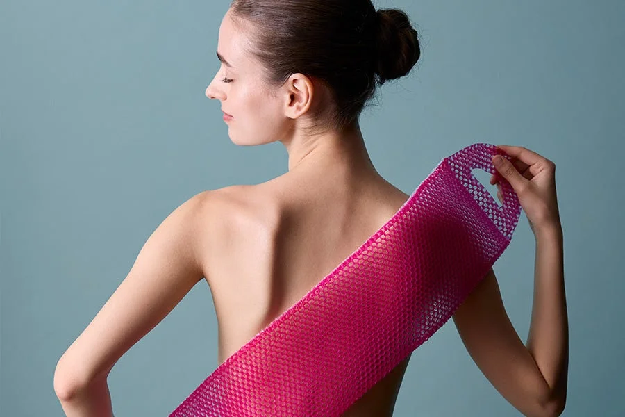 Woman with pink bath mitt on her back