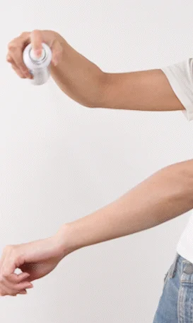 人物が腕にスプレーを吹きかけている様子
