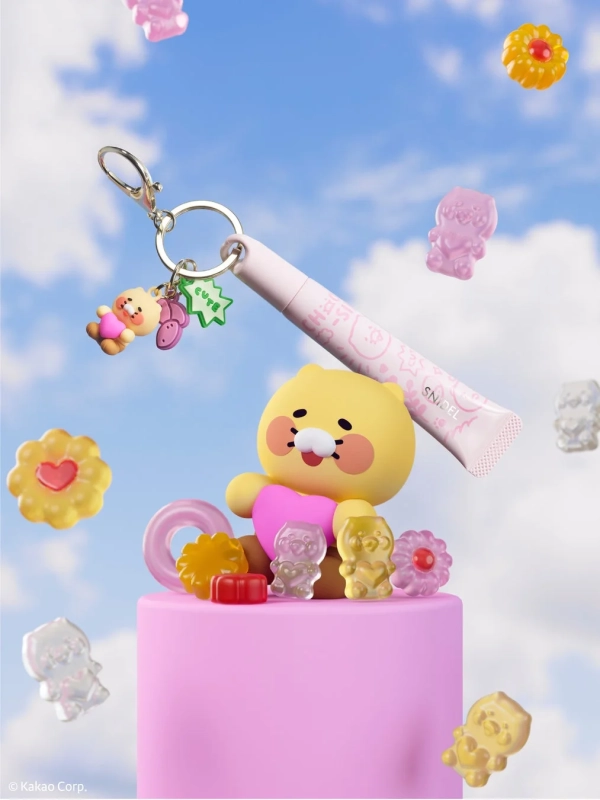 カカオフレンズのライアンがピンクの台座に座り、SNIDELとコラボしたリップやグミのような装飾品に囲まれている