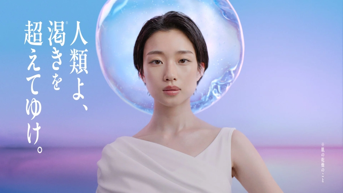 青とピンクの背景に白い衣装の若い女性と「人類よ、渇きを超えてゆけ。」のメッセージ