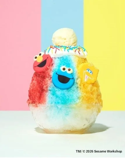 セサミストリートのキャラクター(エルモ、クッキーモンスター、ビッグバード)が飾られた、赤、青、黄色のカラフルなかき氷です。