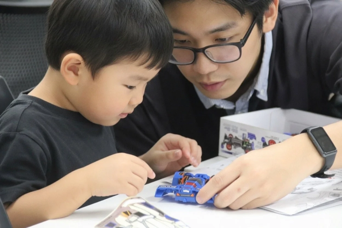 男性と子供が一緒に青いおもちゃの車を組み立てている様子です。