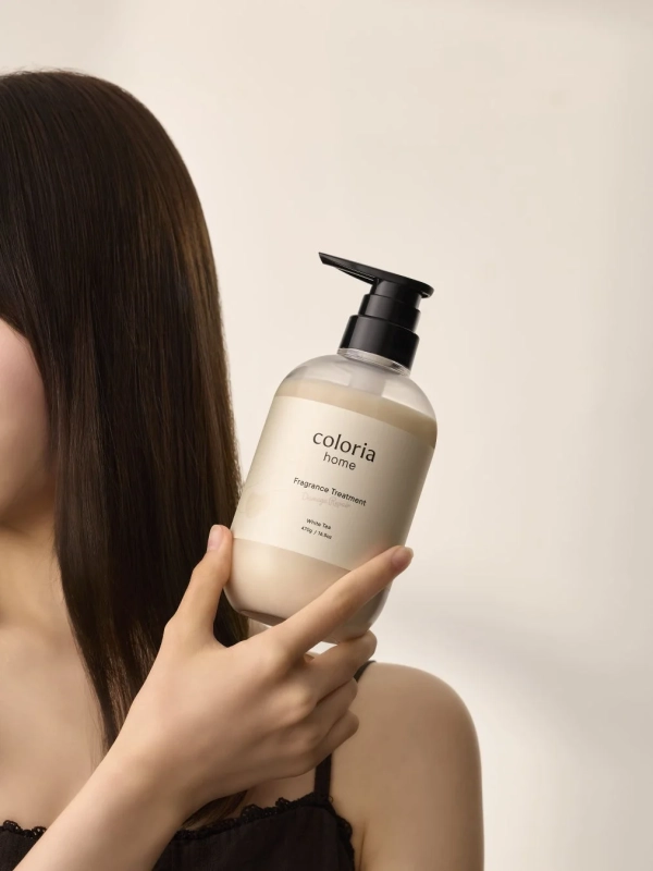 女性がColoria Homeのフレグランストリートメントボトルを持っている様子